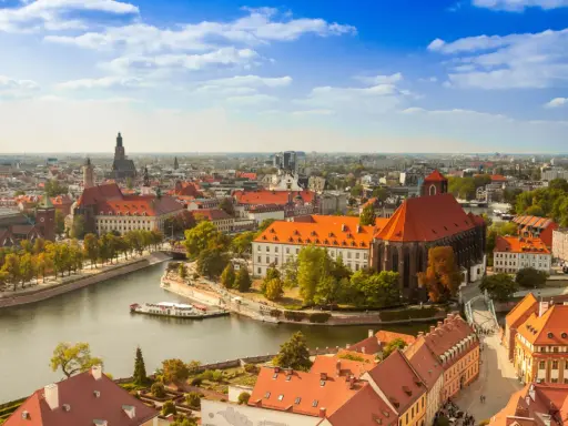 Widok na Ostrów Tumski we Wrocławiu, idealne miejsce na city break z Wrocławia. Rzeka, zabytkowe budynki i błękitne niebo.