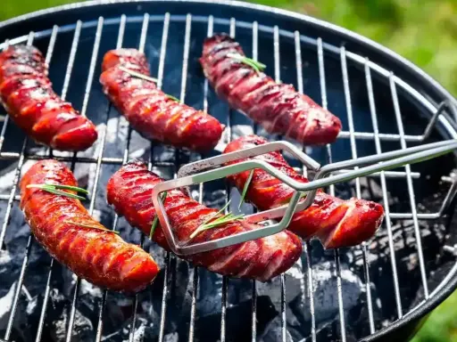 Pyszna kiełbasa z grilla, rumiana i soczysta, z gałązkami rozmarynu, pieczona na węglu.