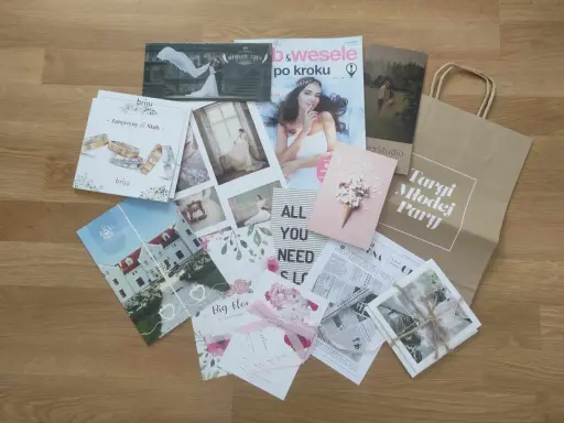 Materiały z targów ślubnych: magazyny, zaproszenia, zdjęcia i torba z napisem "Targi Młodej Pary".