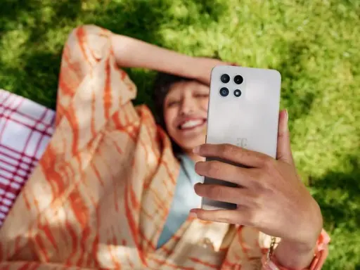 Uśmiechnięta osoba robi selfie na trawie, ciesząc się czasem przed ekranem.