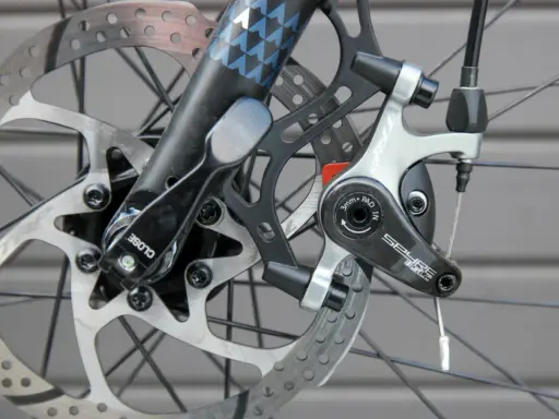 Nahaufnahme einer Fahrradscheibenbremse. Die Bremsbeläge sind sichtbar, was einen Hinweis darauf gibt, wann bremsscheiben wechseln.