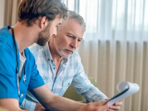 Lekarz omawia z pacjentem wyniki badań. Czy biopsja prostaty boli? Pacjent z niepokojem słucha wyjaśnień.