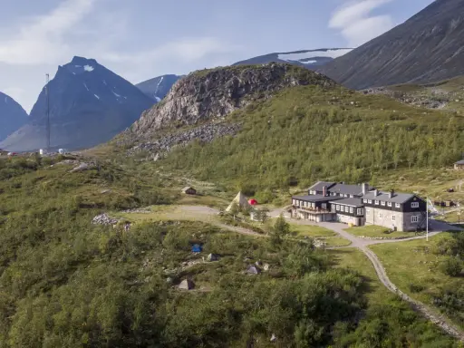 STF Kebnekaise fjällstation med tält och fjäll i bakgrunden. En plats för äventyr och naturupplevelser.