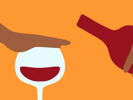 En hand stoppar ett glas rött vin medan en flaska hälls. Kanske en påminnelse om att vara försiktig med alkohol, särskilt om man tar medicin som Diamox.