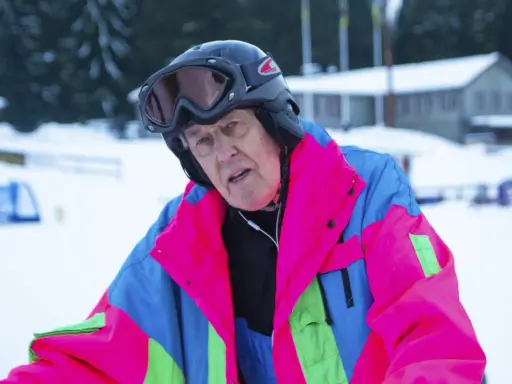 Äldre man i färgglad skidjacka och hjälm, redo för backen. Kanske en veteran från Edsbyn skidor.