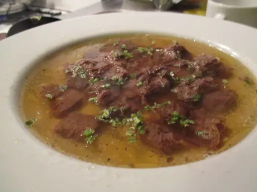 Ein Teller mit Tafelspitz, zartes Rindfleisch in Brühe, garniert mit frischen Kräutern. Ein Klassiker des Tafelspitz Rezepts.