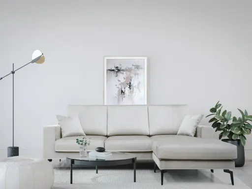 Divano angolare color crema, con tavolino rotondo in vetro e pouf bianco. Le misure del divano angolare sono perfette per questo spazio.