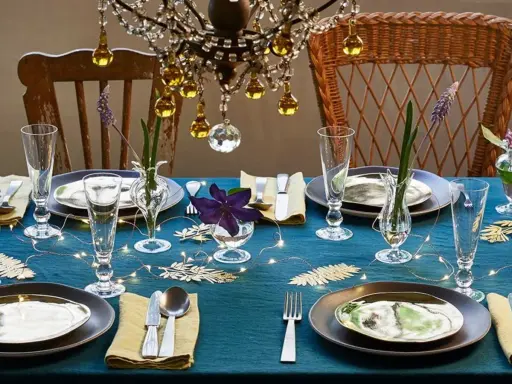 Une table dressée avec élégance, des verres étincelants et des fleurs délicates. L'art de la table est célébré sous un lustre scintillant.