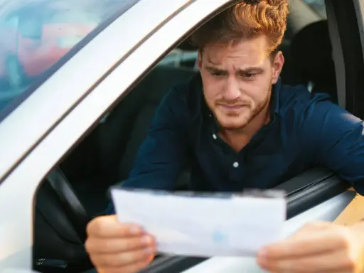 Hombre preocupado mira un papel, preguntándose cuanto tarda una multa en aparecer en mi DGT.