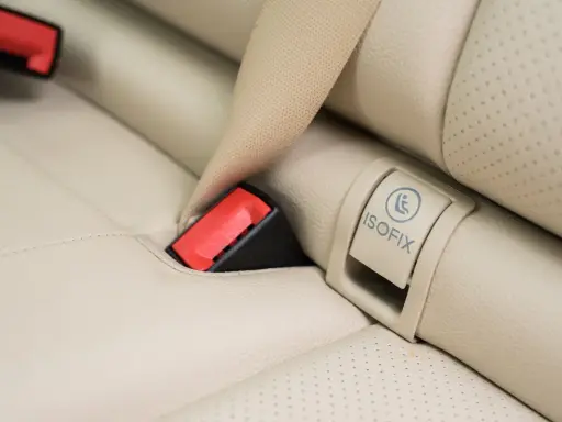 Zapięcie pasa bezpieczeństwa i oznaczenie ISOFIX na jasnej, skórzanej kanapie samochodowej. Czy baza isofix pasuje do każdego fotelika?