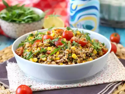 Una gustosa insalata di farro estiva con pomodorini, mais e rucola, perfetta per un pasto leggero e nutriente.