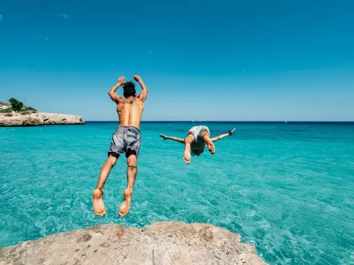Due ragazzi si tuffano in un mare cristallino, un'idea perfetta per chi cerca dove andare in vacanza con pochi soldi in Italia.