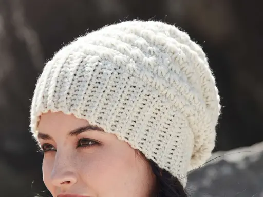 Mujer con gorro de ganchillo blanco con patrón texturizado. ¡Encuentra gorros de ganchillo patrones gratis para crear el tuyo!