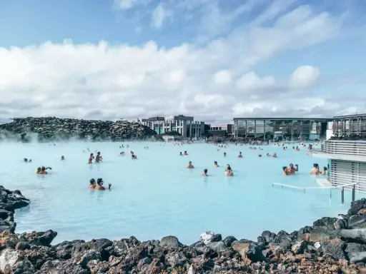 Relaks w Blue Lagoon Islandia. Ludzie kąpią się w mlecznoniebieskiej wodzie geotermalnej otoczonej wulkanicznymi skałami.