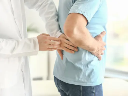 Lekarz bada pacjenta z bólem w boku, sugerującym rozbijanie kamieni nerkowych.