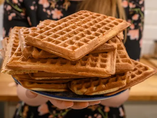 Une assiette débordante de gaufres dorées, parfaites pour une recette de gaufres croustillantes et moelleuses. Un délice à partager !