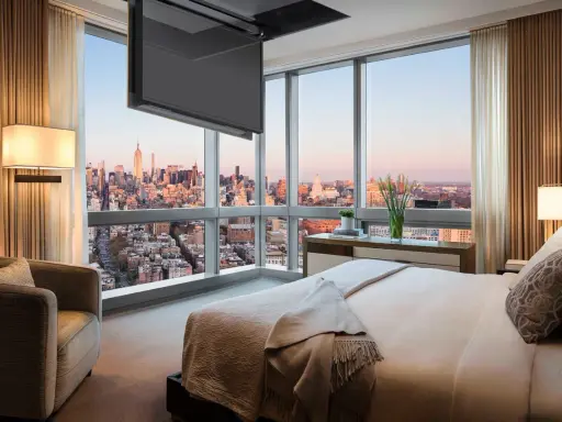 Camera da letto con vista su New York, dove una tv nascosta a soffitto scompare quando non serve, lasciando spazio al panorama.