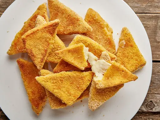 Mozzarella in carrozza al forno, triangolini dorati e croccanti con cuore filante di formaggio fuso, serviti su un piatto bianco.
