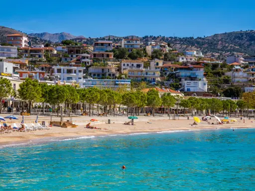 Albania, wrzesień, pogoda idealna na plażowanie. Słoneczny dzień, turkusowe morze i miasteczko na wzgórzu.