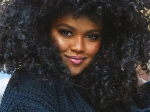A woman with voluminous, natural curly hair, showcasing beautiful hairstyles for natural curly hair.