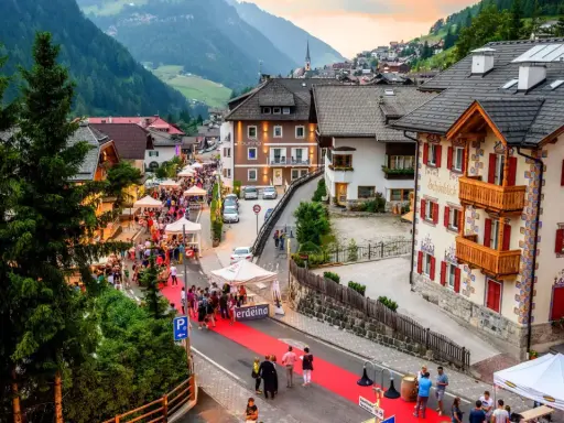 Festa a Santa Cristina Val Gardena con gente, bancarelle e un tappeto rosso.