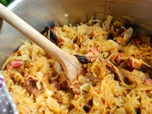 Gotujesz bigos? W garnku widać kapustę kiszoną z różnymi rodzajami mięsa, jak wieprzowina i kiełbasa. Idealne jakie mięso do bigosu!