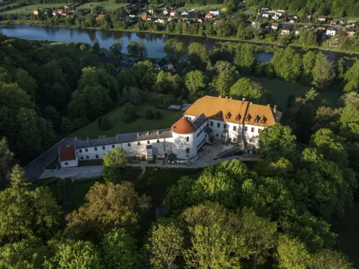 Zamek w Lesku otoczony zielenią, z widokiem na rzekę i miasteczko.
