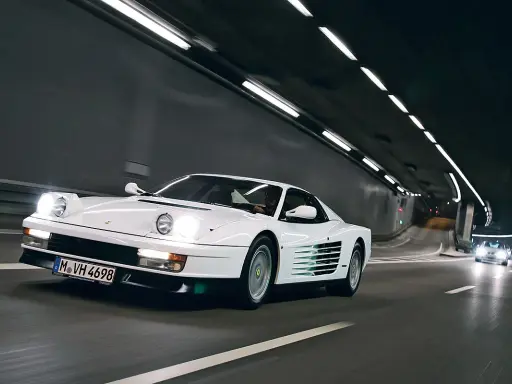Weißer Ferrari Testarossa fährt durch einen beleuchteten Tunnel.