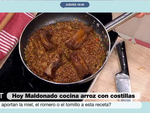 Un delicioso arroz con costillas se cocina en una sartén, con trozos de carne jugosa y arroz dorado.