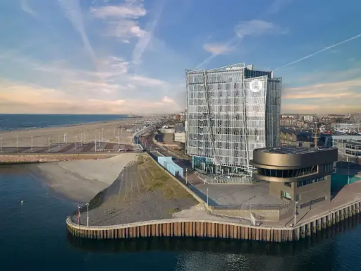 Modernes Hotel am Meer mit Glasfassade, Strand und Hafen.
