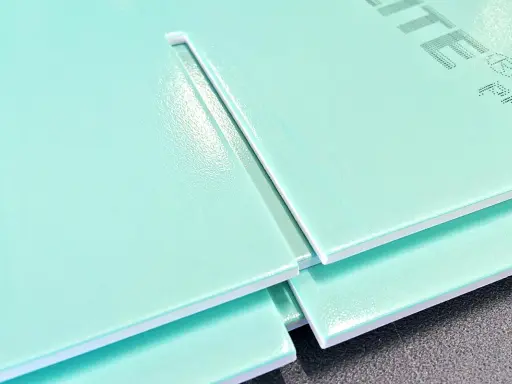 Mehrere hellgrüne Hartschaumplatten liegen übereinander. Eine Platte zeigt eine gerade Schnittkante, die das Schneiden von Hartschaumplatten verdeutlicht.