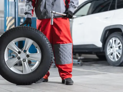 Mecánico con una rueda motriz de coche lista para ser instalada.