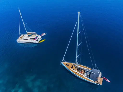 Zwei Segelboote, ein Katamaran und eine Yacht, liegen friedlich auf dem tiefblauen Meer.