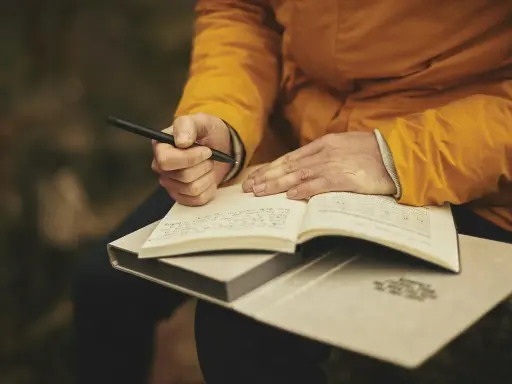 Mani che scrivono su un quaderno aperto, ispirate dalle riviste letterarie italiane.