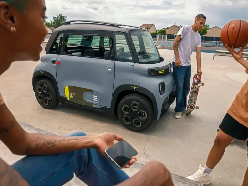 Jóvenes con patineta y balón de baloncesto cerca de un coche gris. ¡Qué ganas de tener el permiso AM que puedo conducir!