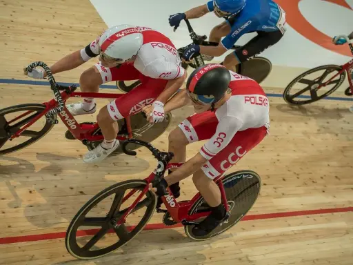 Wyścig kolarski madison. Dwóch kolarzy w biało-czerwonych strojach jedzie na torze.
