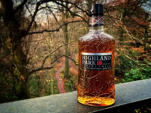Butelka whisky Highland Park 18 Year Old na tle jesiennego lasu.