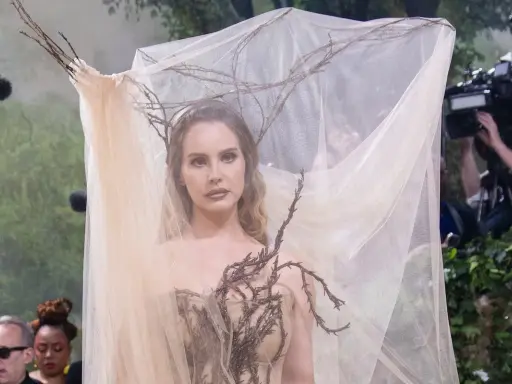 Lana Del Rey at the Met Gala, adorned in a ethereal gown with branches and sheer veil, looking like a forest nymph.