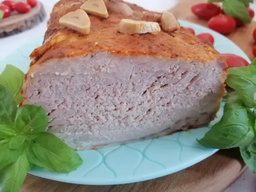 Soczysty schab pieczony w mleku, z czosnkiem i bazylią, prezentuje się apetycznie na talerzu.