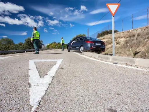 Agentes de tráfico controlan la circulación en una carretera. Un coche se detiene, quizás preguntándose cuánto tarda en llegar una multa.