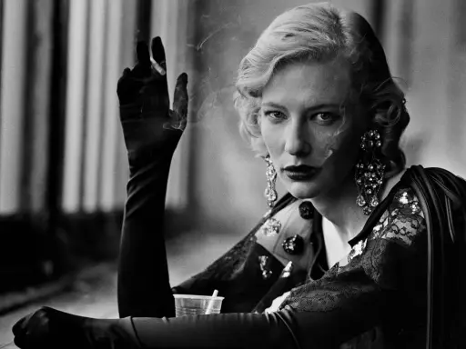 A woman with blonde hair and dramatic earrings smokes, a signature element in many Peter Lindbergh famous photos.