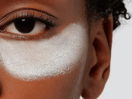 Primo strato di cipria prima del fondotinta, evidenzia la texture della pelle e la preparazione per un makeup impeccabile.