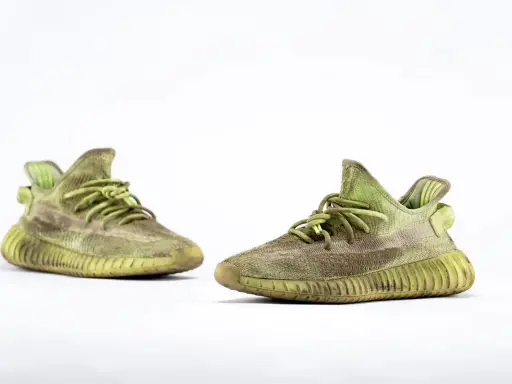 Para zielonych adidas Yeezy 350 z charakterystyczną, prążkowaną podeszwą, gotowe na miejskie przygody.