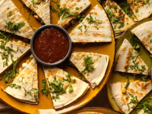 Pyszna quesadilla z mięsem mielonym, pokrojona w trójkąty, podana z salsą i zielonym sosem.