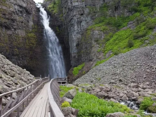 Vacker vattenfall i en ravin, med en träbro som leder besökare längs en av Sveriges många vandringsleder.