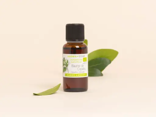 Flacon de baume de copahu, une oléorésine naturelle aux vertus calmantes et apaisantes, entouré de feuilles vertes.