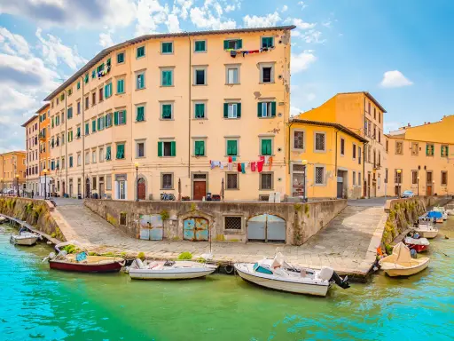 Canali di Livorno, un'idea per cosa vedere a Livorno in un giorno. Case colorate e barche sull'acqua turchese.