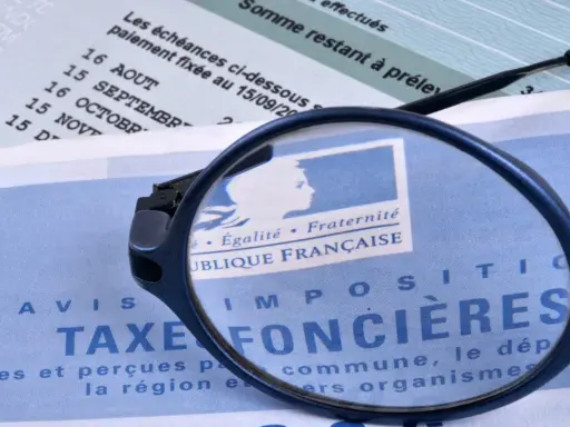 Loupe sur un avis de taxe foncière par commune. Le document mentionne "République Française" et des dates d'échéances.