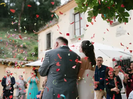 Novios bajo una lluvia de confeti en forma de corazón. Los invitados lanzan confeti, creando un ambiente festivo, perfecto para las canciones de boda.
