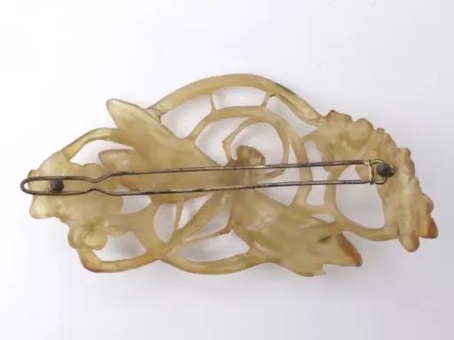 Pince à cheveux Art Nouveau en corne sculptée, évoquant le style de Lucien Gaillard, avec des motifs floraux et une libellule.